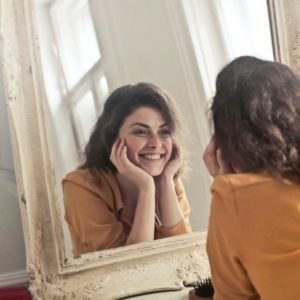 beautiful woman smiling into a mirror